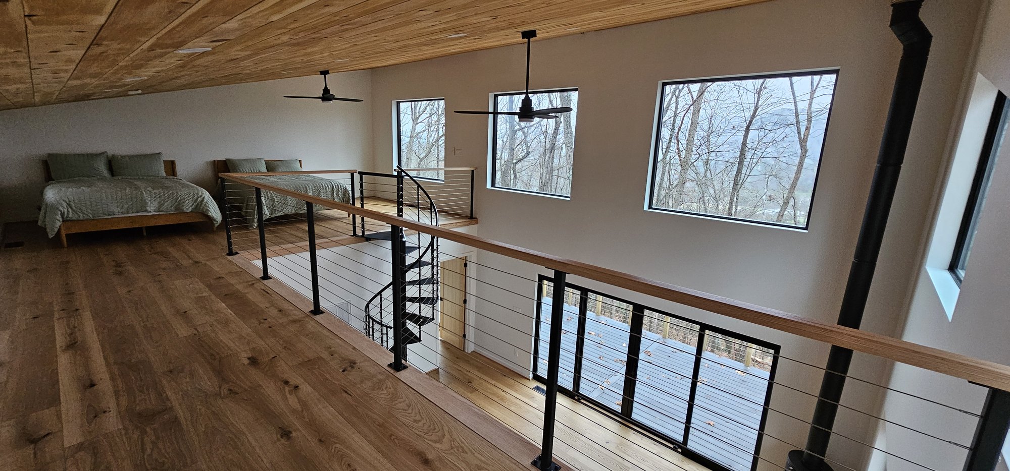 Modern cabin loft with cable railing and spiral staircase