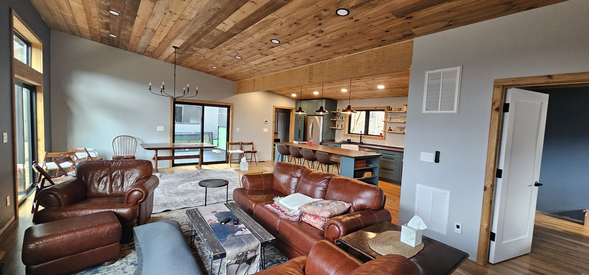 Open plan living, kitchen, and dining with wood ceiling and live-edge island